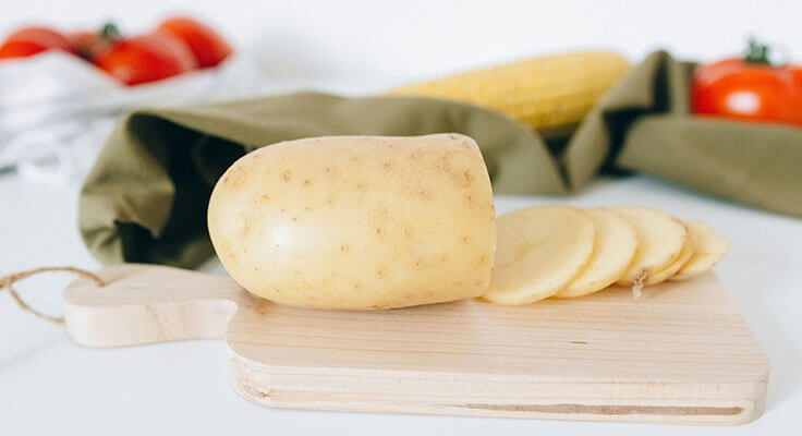 Sliced potato on wooden cutting board.