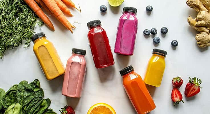 Colorful juice bottles with fruits and vegetables.