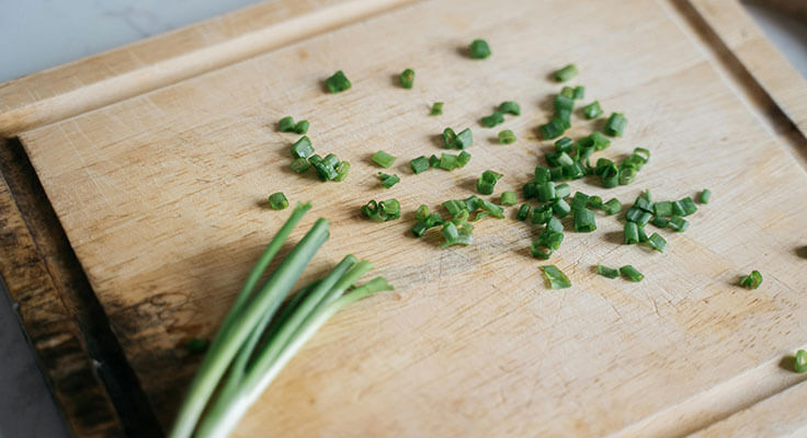 Chopped green onions on wooden cutting board
