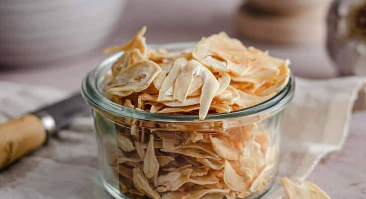 Homemade dehydrated garlic chips in glass jar
