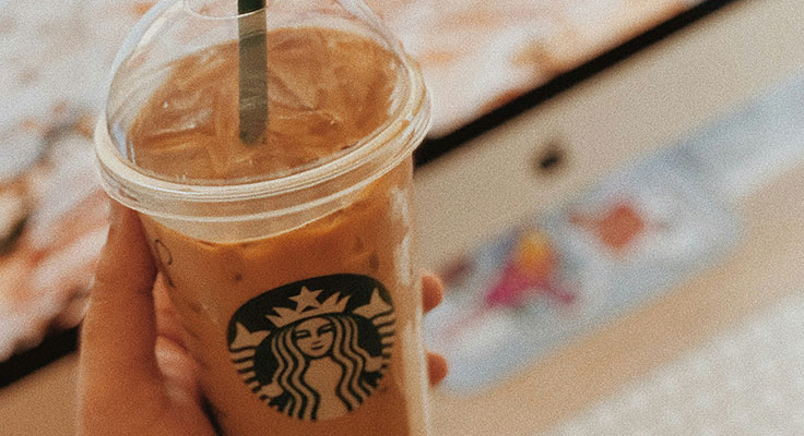 Hand holding iced coffee from Starbucks.