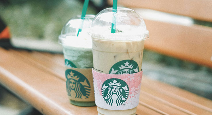Two Starbucks iced drinks on a bench