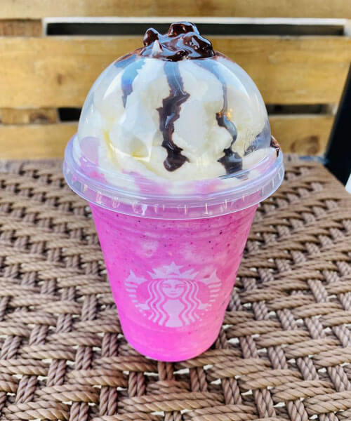 Pink Starbucks drink with whipped cream and chocolate drizzle.