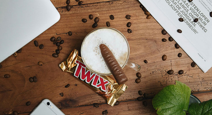 Coffee with Twix candy bar on table