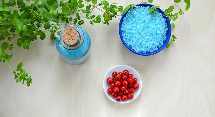 Herbs, blue salt, red berries on table.