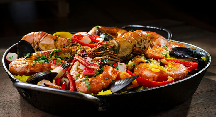 Seafood paella in a black pan.