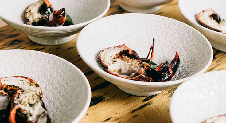 Lobster dishes on white patterned bowls.