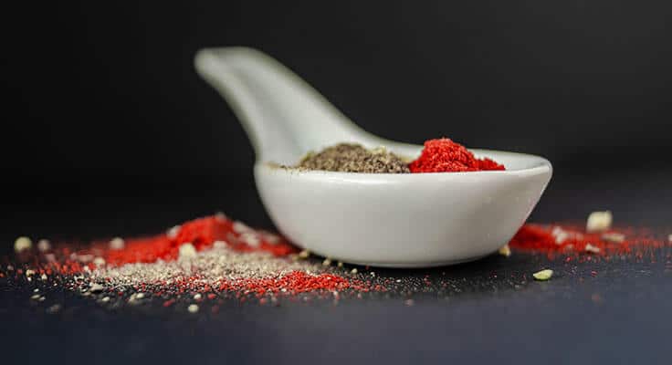 Red and black spices in a white spoon