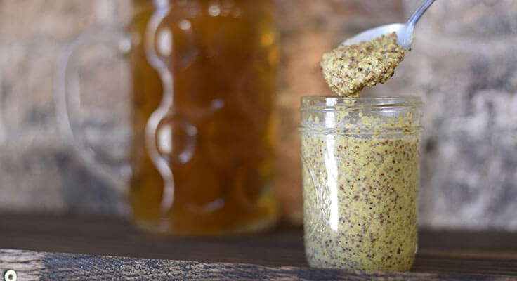 Glass jar of grainy mustard with spoon