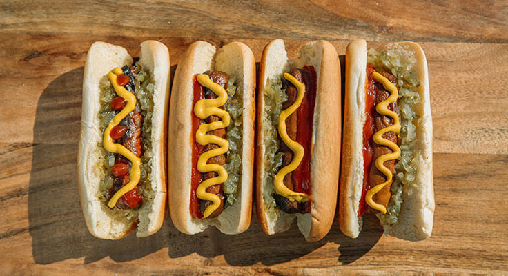 Five hot dogs with mustard and relish.