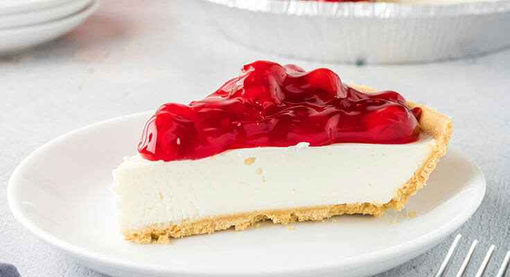 Slice of cherry-topped cheesecake on white plate.