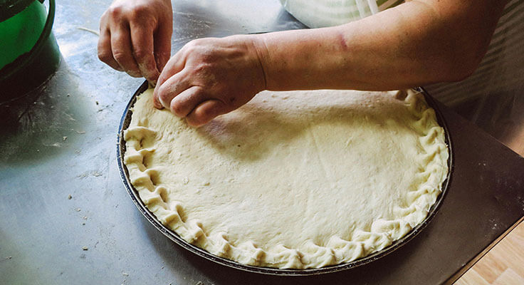 Person crimping pie crust edges.