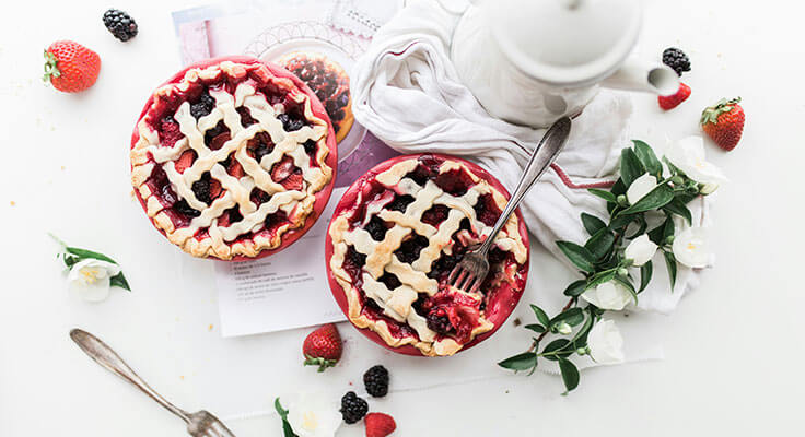 Two berry pies with lattice crust on table