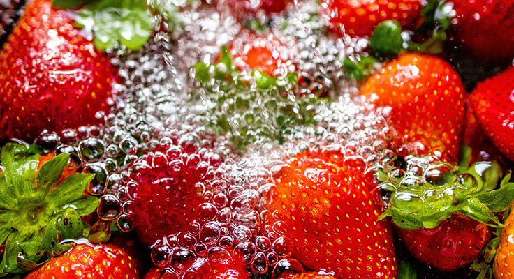 Fresh strawberries washing under water with bubbles.