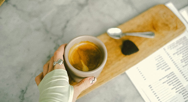 Person holding a cup of coffee on a tray
